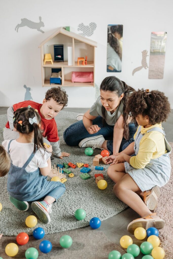An adult sitting on the floor with a small group of young children
